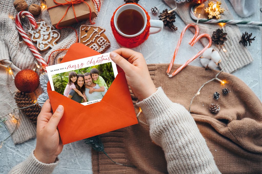 Photo card being opened against a backdrop of Christmas items.